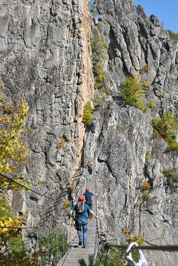 Leute, die die Brücke am Klettersteig Nelson Rocks überqueren, ideal für Kletterfreunde! 