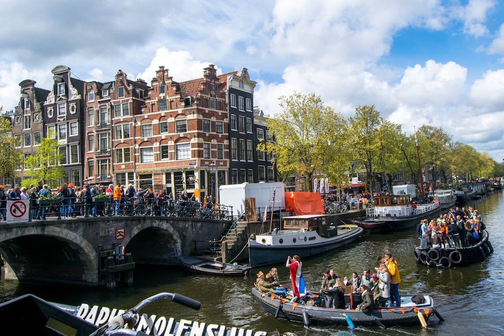 Boat in canal on King's Day in Amsterdam, the best holiday in Amsterdam. Celebrate this holiday this spring in Amsterdam with insider tips! #amsterdam #Netherlands #travel #europe