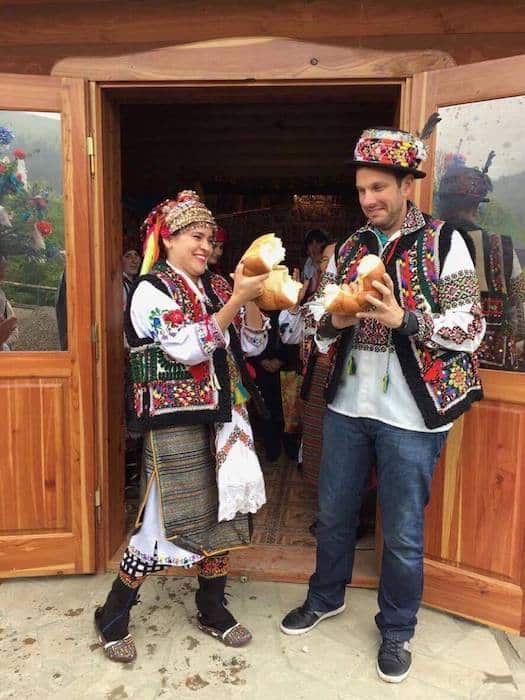 Couple breaking bread in traditional Ukrainian ceremony for elopement in Ukraine. 