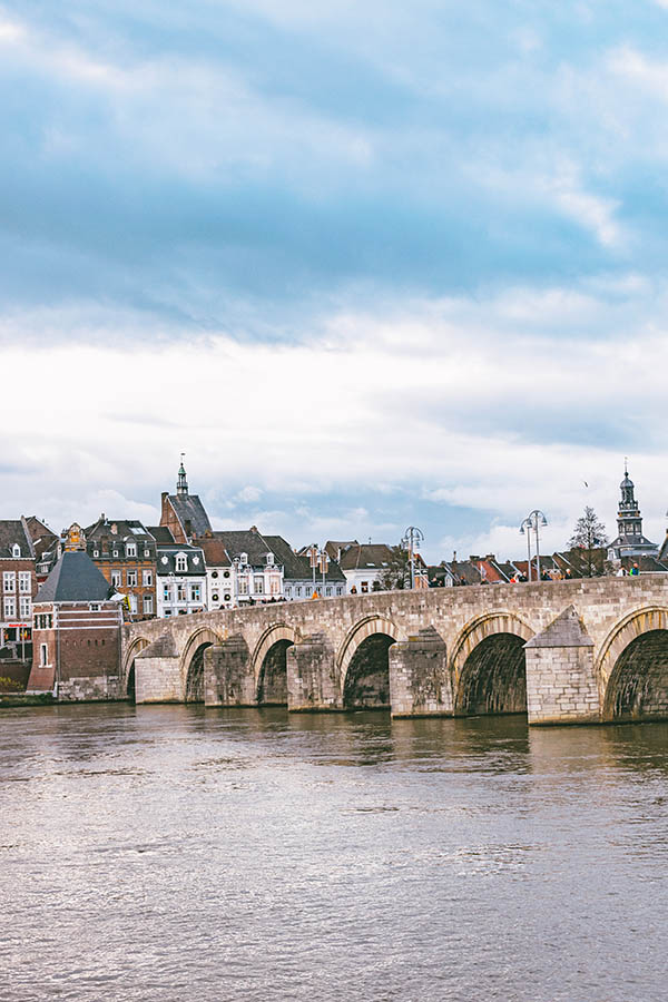 Beautiful view of the Maas river with bridge with Maastricht historic city center in the distance.  Enjoy the river views is one of the best things to do in Maastricht