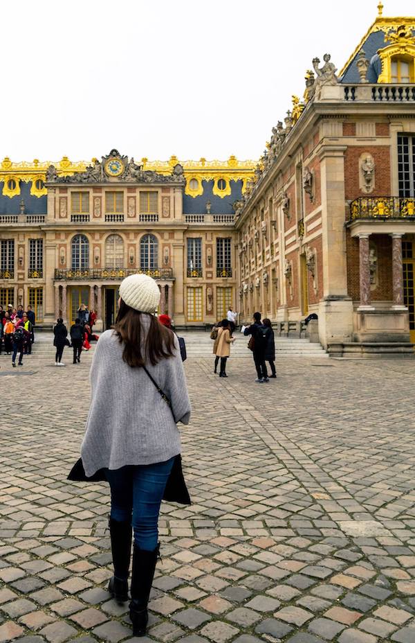 Girl walking on the grounds of Versailles. Read tips for visiting Versailles, how to avoid the crowds at Versailles, and what to know before your visit to Versailles! #travel #versailles #france