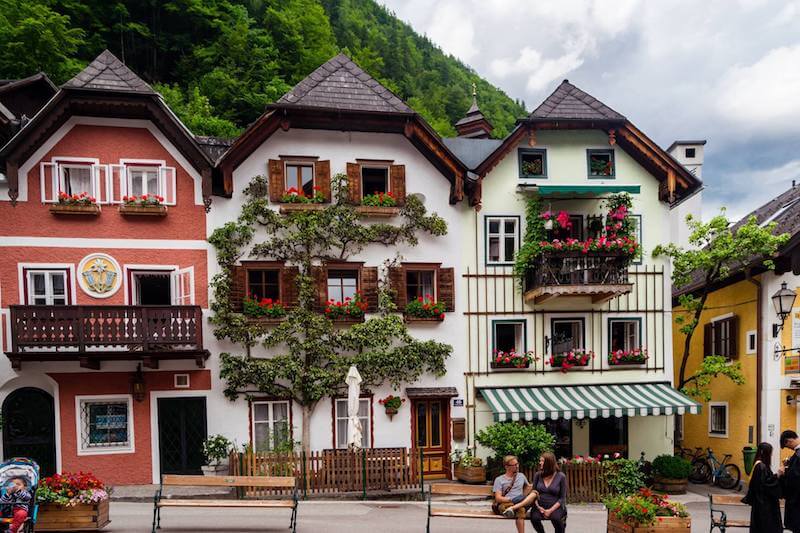Beautiful houses with wooden shutters and flower boxes in the windows along the main square of Hallstatt, Austria. #travel #hallstatt