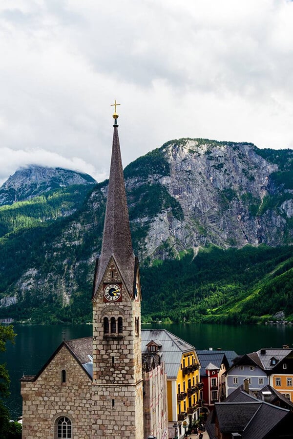 Beautiful view of the church in Hallstatt, Austria with a stunning view of the mountains surrounding the Hallstätter See. Hallstatt is considered one of the most beautiful places to visit in Austria! #Austria #Hallstatt