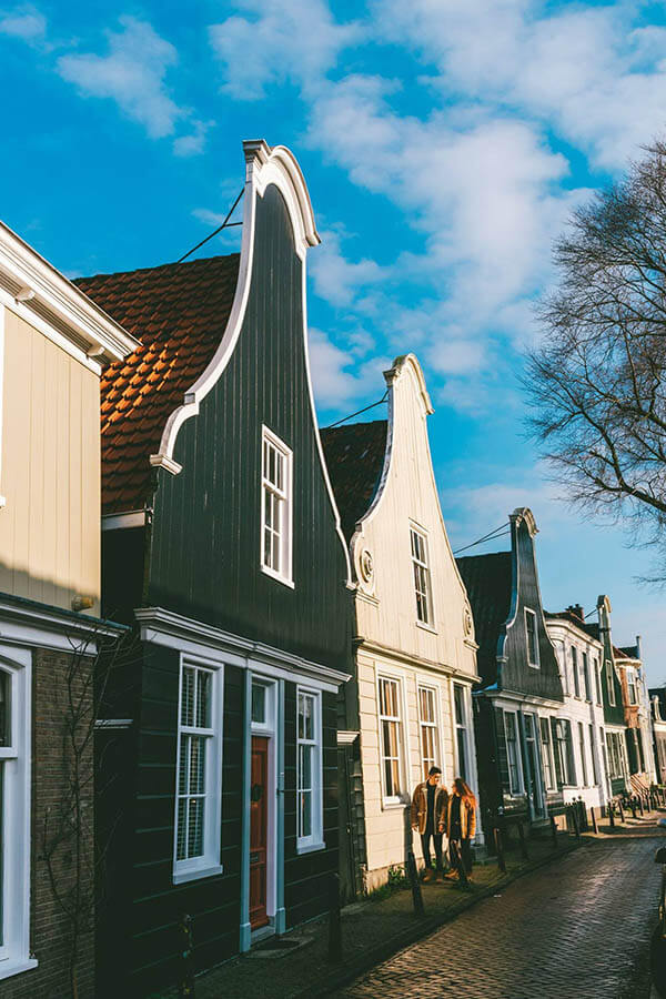 Couple walking along Nieuwendammerdijk, one of the most beautiful streets in Amsterdam that you have to see!