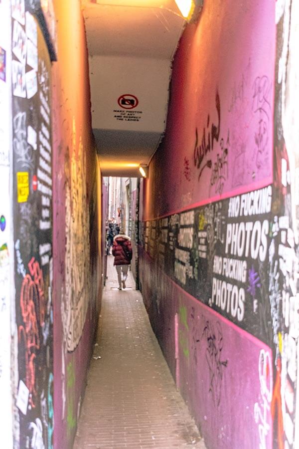 Trompettersteeg, the narrowest street in Amsterdam, is at the heart of Red Light District.  Graffiti states no photos!