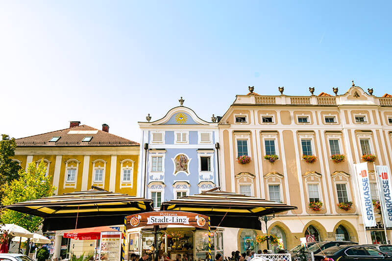 Beautiful Austrian city, Enns, with colorful buildings.  Read how to reduce your budget while traveling in Austria. #travel #austria