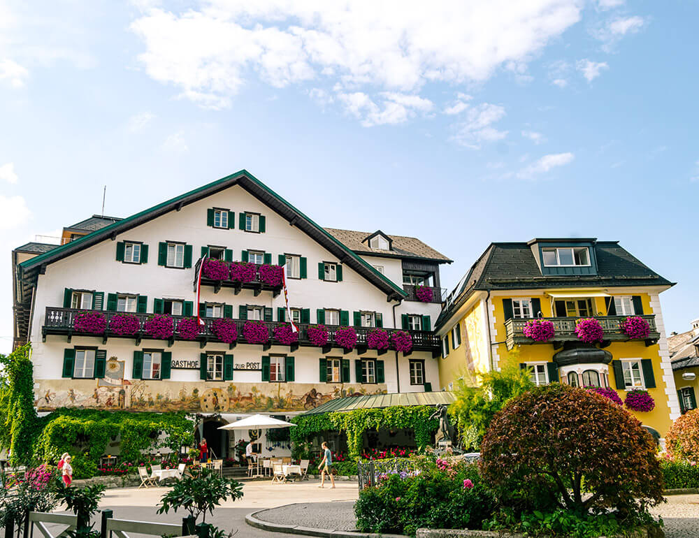 Beautiful hotel with wooden balcony and flowers in the city center of St. Gilgen.  Read where to stay in St. Gilgen, Austria!