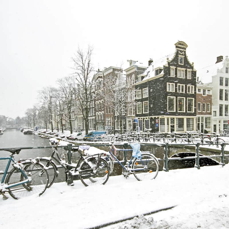 Snowy canal in Amsterdam during winter. Read about the best things to do in winter in Amsterdam. #amsterdam #netherlands