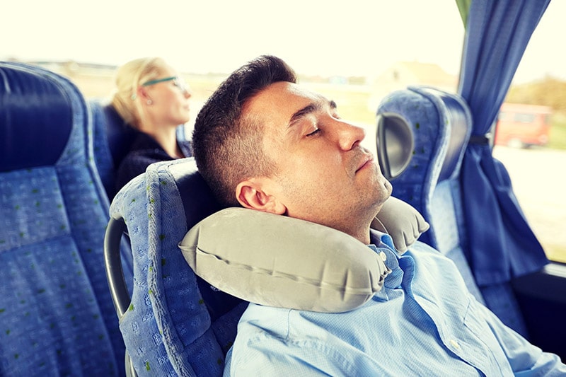 Photo of man sleeping on overnight bus in the United States. Read more tips for surviving long bus trips and what to know before taking a Greyhound bus in the United States.