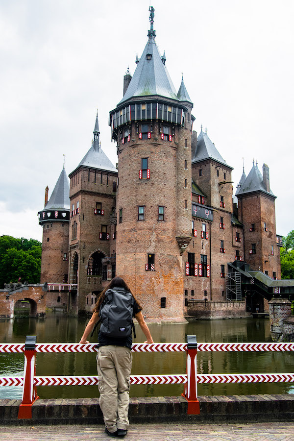 Man admiring castle wearing a carry-on bag. Read
