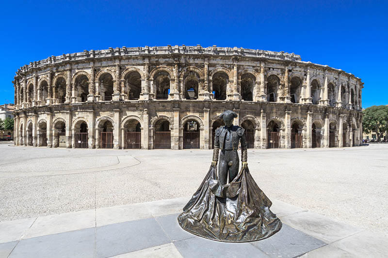 Bullfighter sculpture in front of the old Roman Arena in Nimes, France on a sunny day