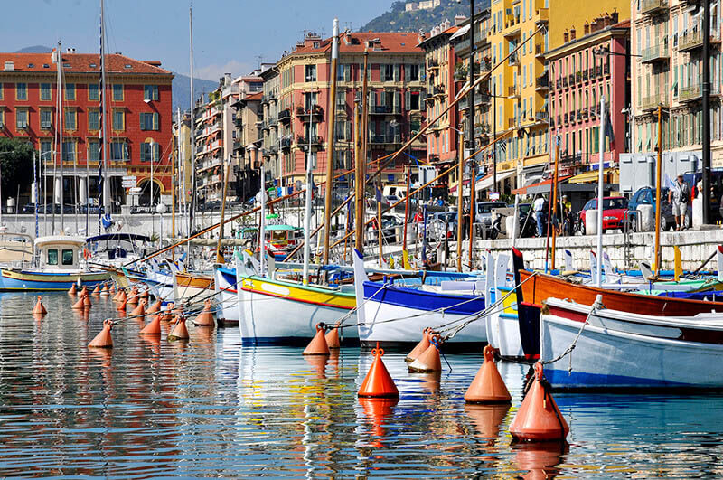 Colorful port of Nice, France with floating boats and reflection of houses in the water