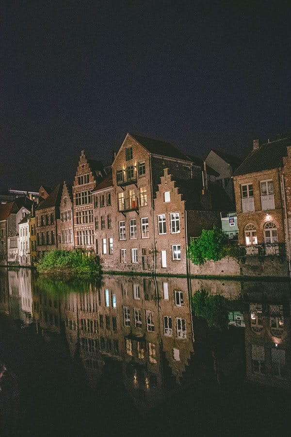 Beautiful former guild houses in Ghent, Belgium along the Leie River after sunset with reflection. 
