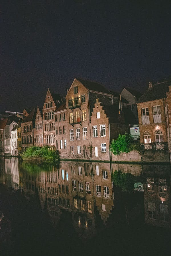 Beautiful former guild houses in Ghent, Belgium along the Leie River after sunset with reflection.