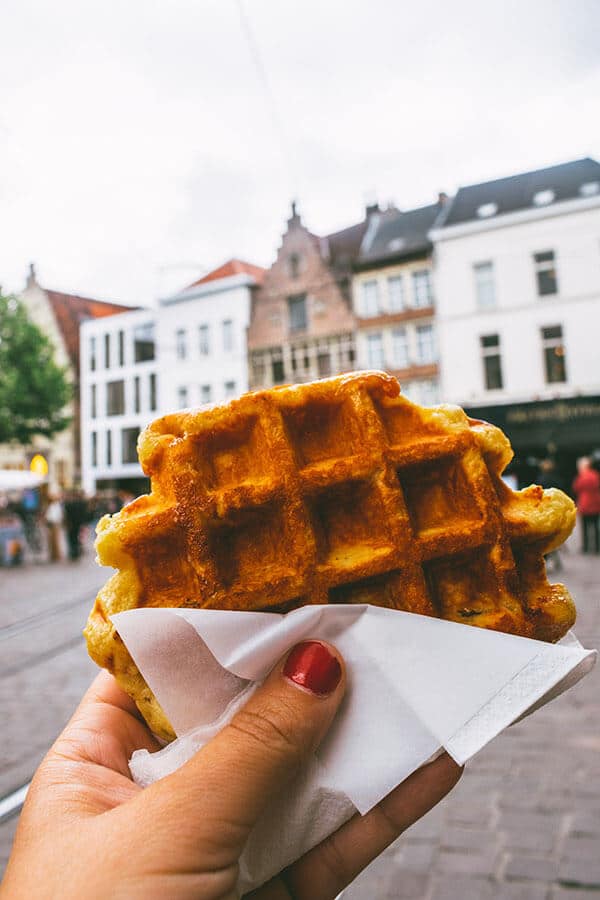 Belgian Luikse waffle in Ghent, Belgium with background of historic city center of Gent