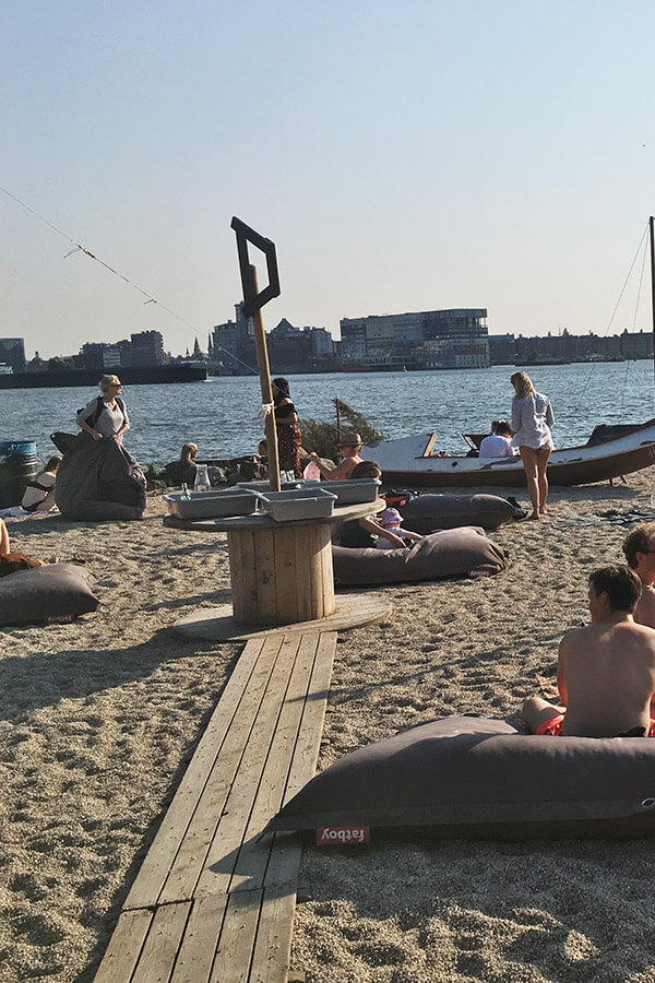 People enjoying a beautiful day on the fake beach in Amsterdam at Pllek, a riverside cafe in Amsterdam Noord. #beach #amsterdam #hipster