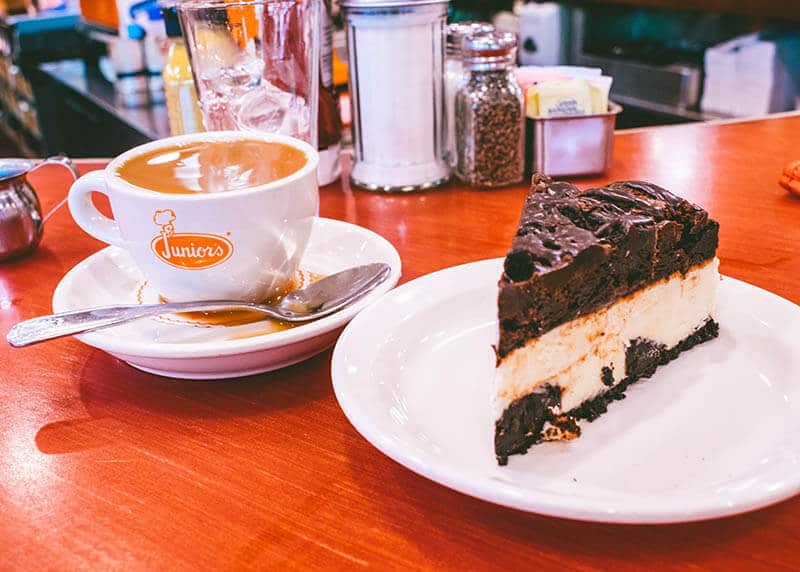 Eine Tasse Kaffee mit einem Stück New Yorker Käsekuchen mit Schokolade von Junior's Cheesecake in Brooklyn.  Dieses klassische New Yorker Diner ist ein Muss für Feinschmecker!