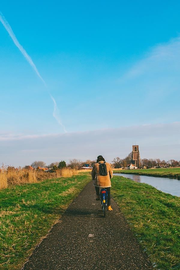 Man cycling in the Dutch countryside outside of Amsterdam.  See the most beautiful places in Holland!