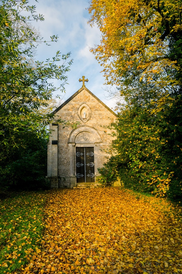 Fall leaves surrounding the family chapel on the grounds of a chateau in France. Read about seven chateaus in France that you can stay at! #travel #france #Normandy