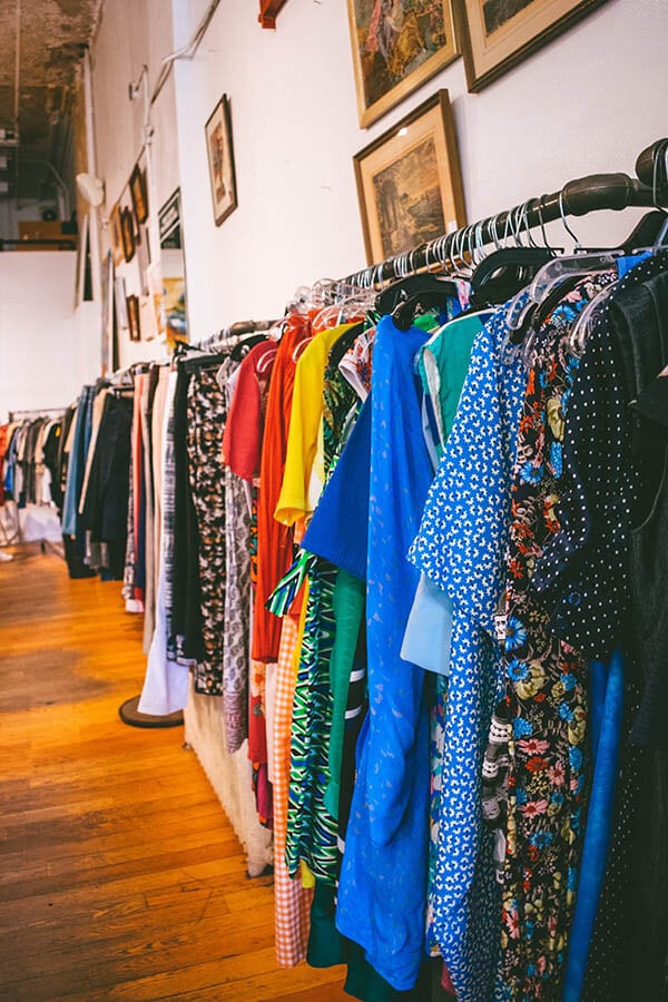 Racks of colorful dresses at Housing Works, one of the popular secondhand stores where you can shop for affordable clothes in New York City!